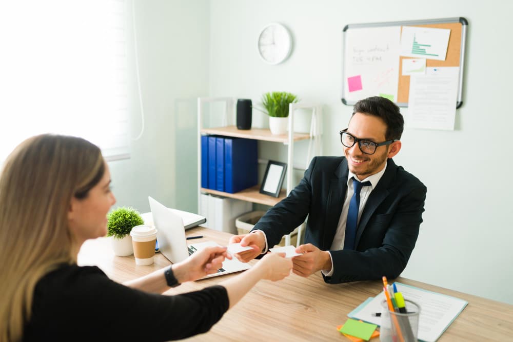 happy-professional-man-smiling-exchanching-business-cards-with-female-colleague-caucasian-woman-giving-her-number-contact-information-latin-man-suit